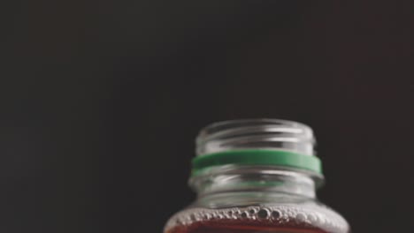 un hombre abre la tapa de una botella de bebida sobre un fondo negro