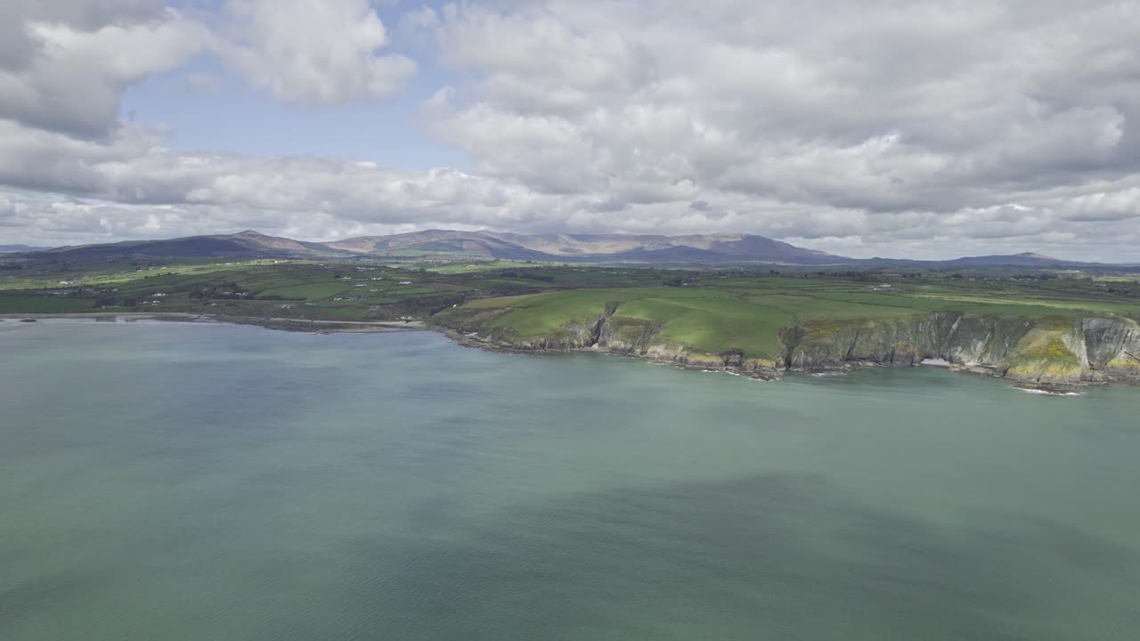 pan lento a la derecha de la costa del cobre waterford con las montañas comeragh y nubes bajas