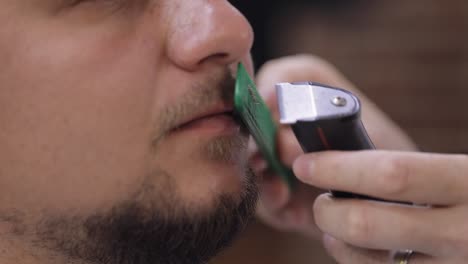 barbero cortando la barba usando un cortador eléctrico, hace un corte de pelo para el novio cliente en la barbería