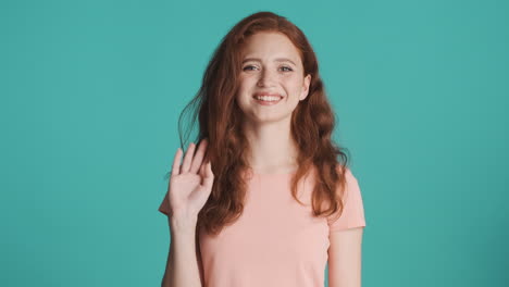 Redheaded-girl-looking-at-camera-on-turquoise-background.