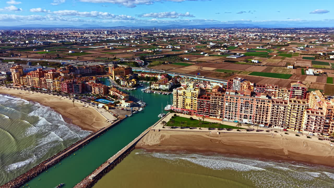 Coastal view of waterfront and green fields in a sunny location with buildings and boats during mid-day