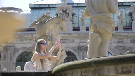 woman capturing sculpture at art event with smartphone a woman capturing a sculpture on her phone adding leisure and fun to the event while admiring the artistic facade of the building