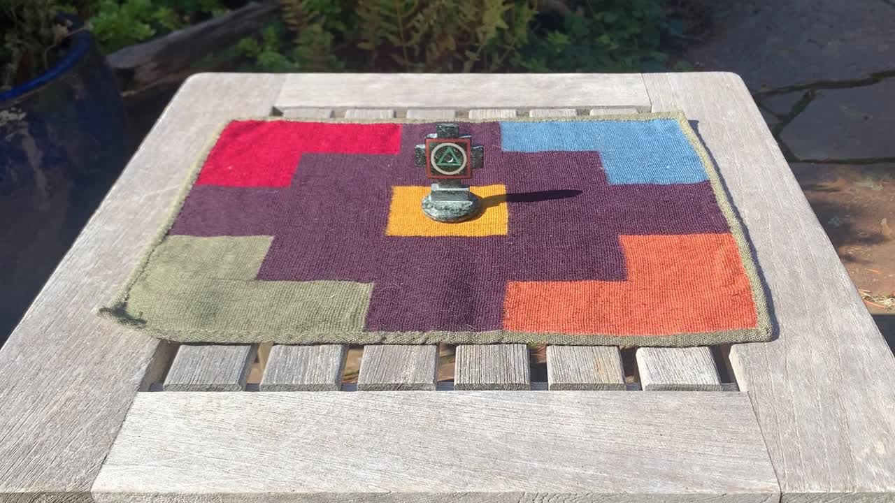 chakana de pie sobre una colorida tela peruana tejida a mano llamada pallay