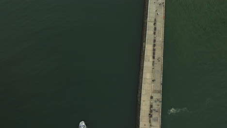 Aerial-footage-showcasing-the-pier-and-coastal-maritime-activity-of-Whitby,-UK