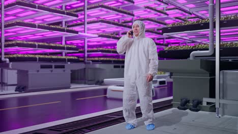 full body of asian male scientist talking on smartphone while standing in vertical farm