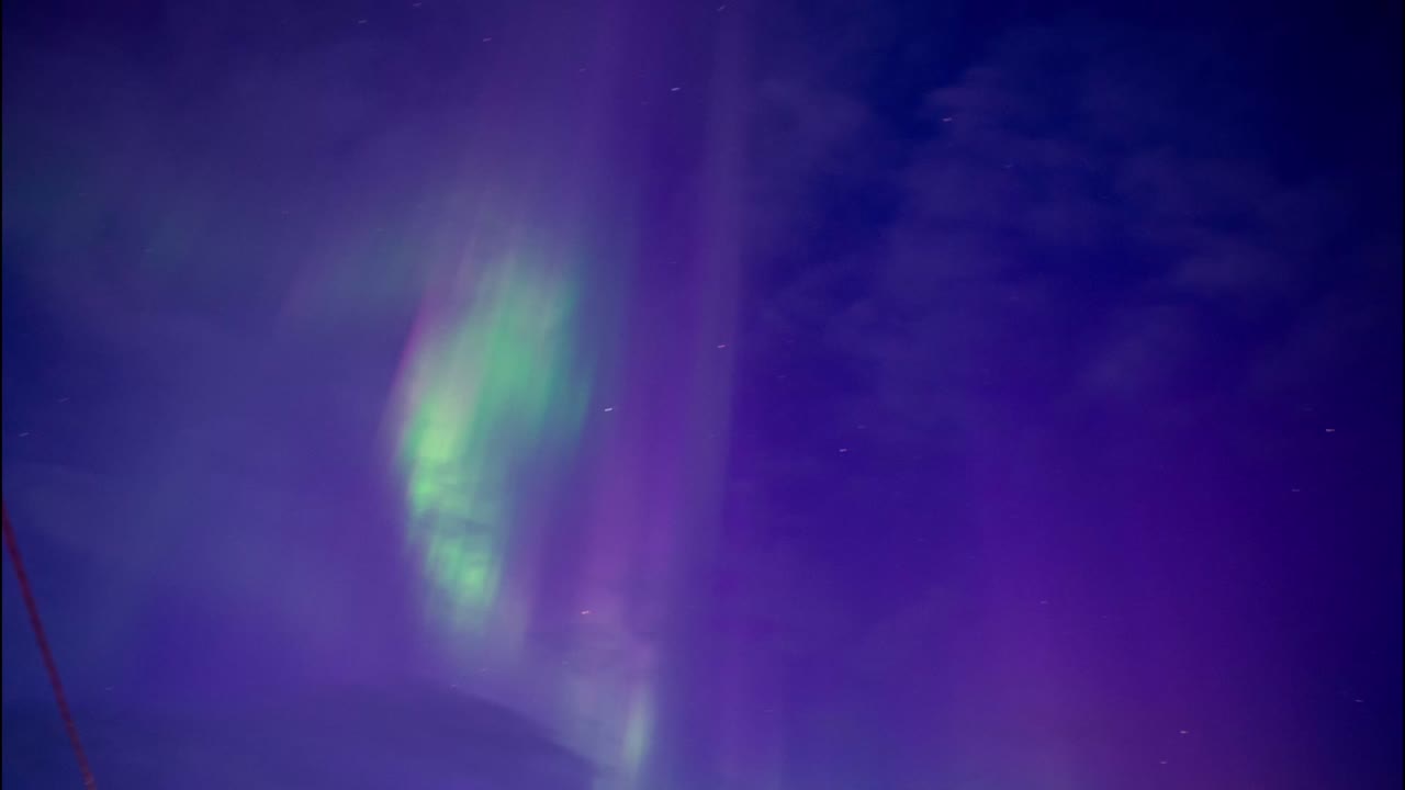 las luces verdes del norte se mueven rápidamente en un cielo nublado