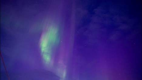 las luces verdes del norte se mueven rápidamente en un cielo nublado