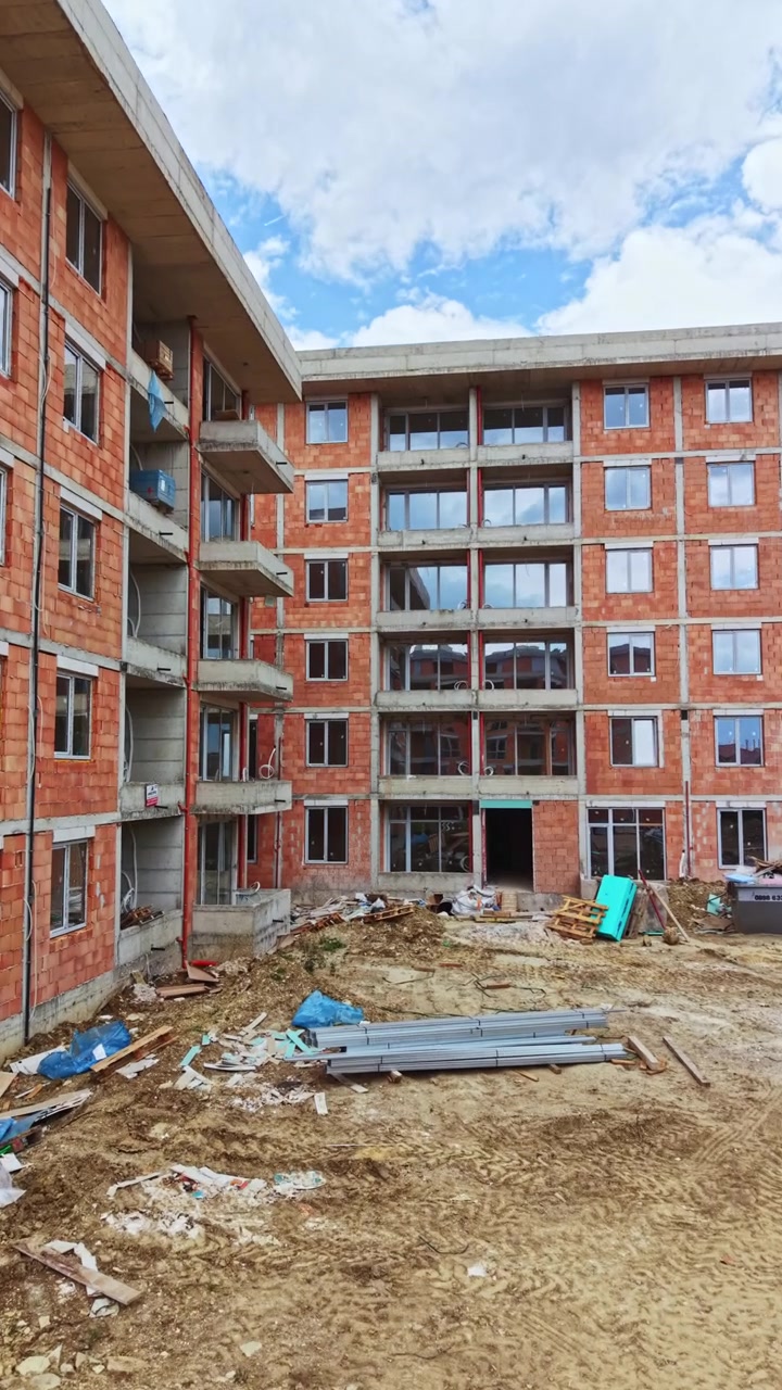 Construção de edifício de múltiplos andares com paredes de tijolo e janelas abertas em área urbana durante o dia em um dia claro.