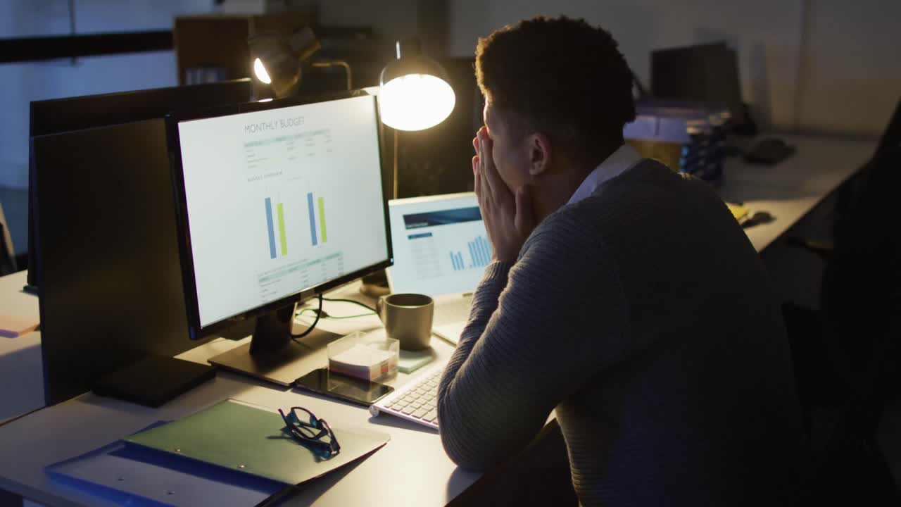 사무실에서 늦게까지 일하는 컴퓨터를 사용하는 피곤한 두 인종의 남자의 비디오