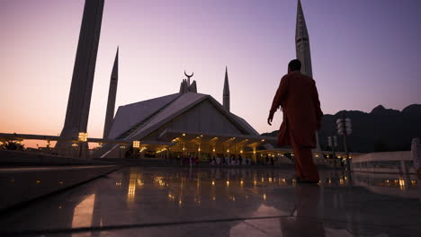 Man-Walking-Towards-Faisal-Mosque-During-Sunset-In-Islamabad,-Pakistan---wide-shot