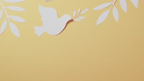 close up of white dove with leaves and copy space on yellow background