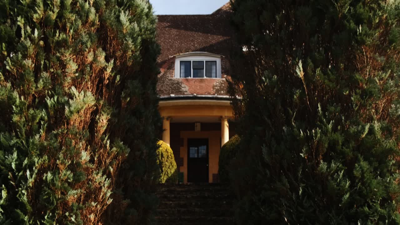 Tilt shot of a beautiful garden with leading stairs up to a mansion entrance.