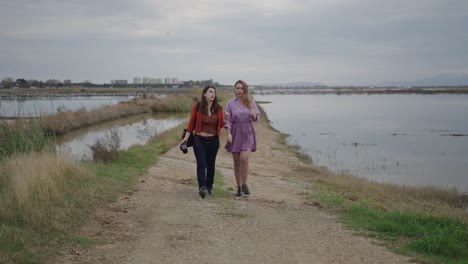 two women walking along a path by a lake