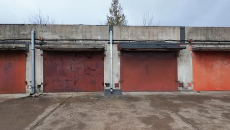 Kamerabewegungsansicht-Einer-Alten,-Rostigen-Vintage-Garage-Aus-Beton,-Die-Tagsüber-Mit-Bunten-Metalltüren-Gebaut-Wurde