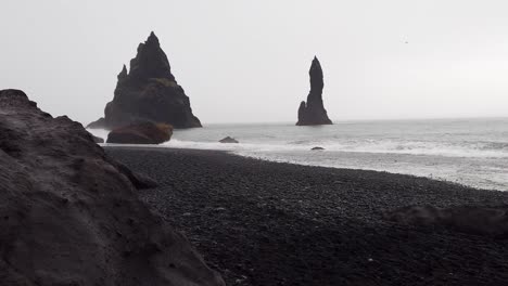 majestic moody view of spiked rocks in the ocean with an overcast sky at reynisfjara black sand beach in iceland