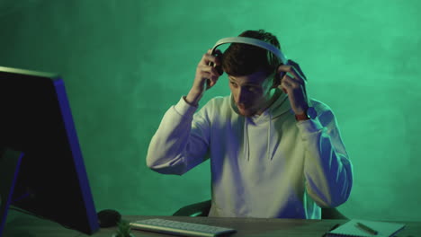 man working with a computer, wireless headphones and a smartphone on a colorful background