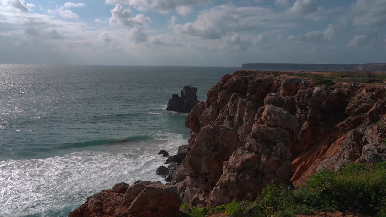 The incredible landscape of a beach, with the foamy white waves breaking on the white sand, surrounded by cliffs