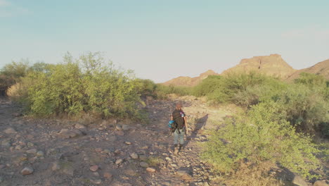 woman on an early morning hike in desert mountains and rocky landscape with backpack