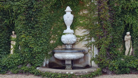 italian greek or english stone water fountain with statues sculptures and vines