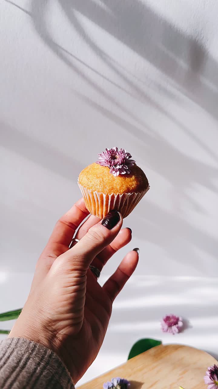 Donna che tiene un cupcake decorato con un fiore viola