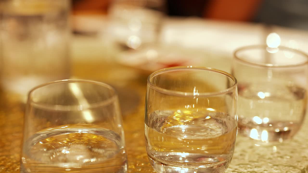 Close-up of water glasses on a table in a warmly lit restaurant, capturing reflections and ambient atmosphere