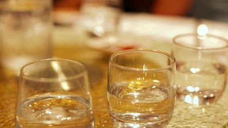 close-up of water glasses on a table in a warmly lit restaurant, capturing reflections and ambient atmosphere