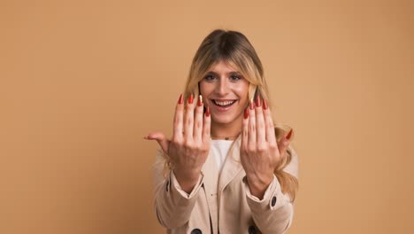 cheerful transgender woman in trench coat showing long red nails