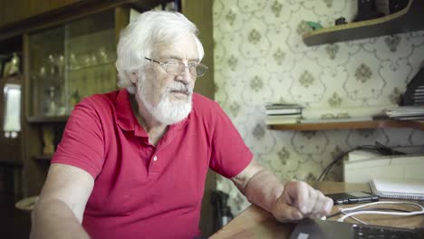 hombre mayor usando computadora portátil en casa