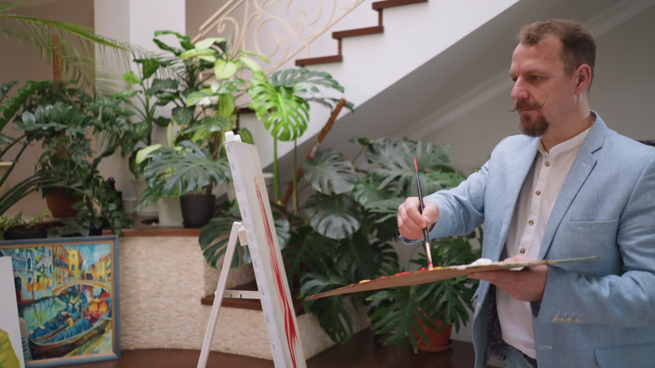 el hombre creador dibuja a una mujer apasionada en el estudio. un artista serio mezcla pinturas al óleo para hacer sombra para pintar en el taller de arte. el maestro trabaja con paleta