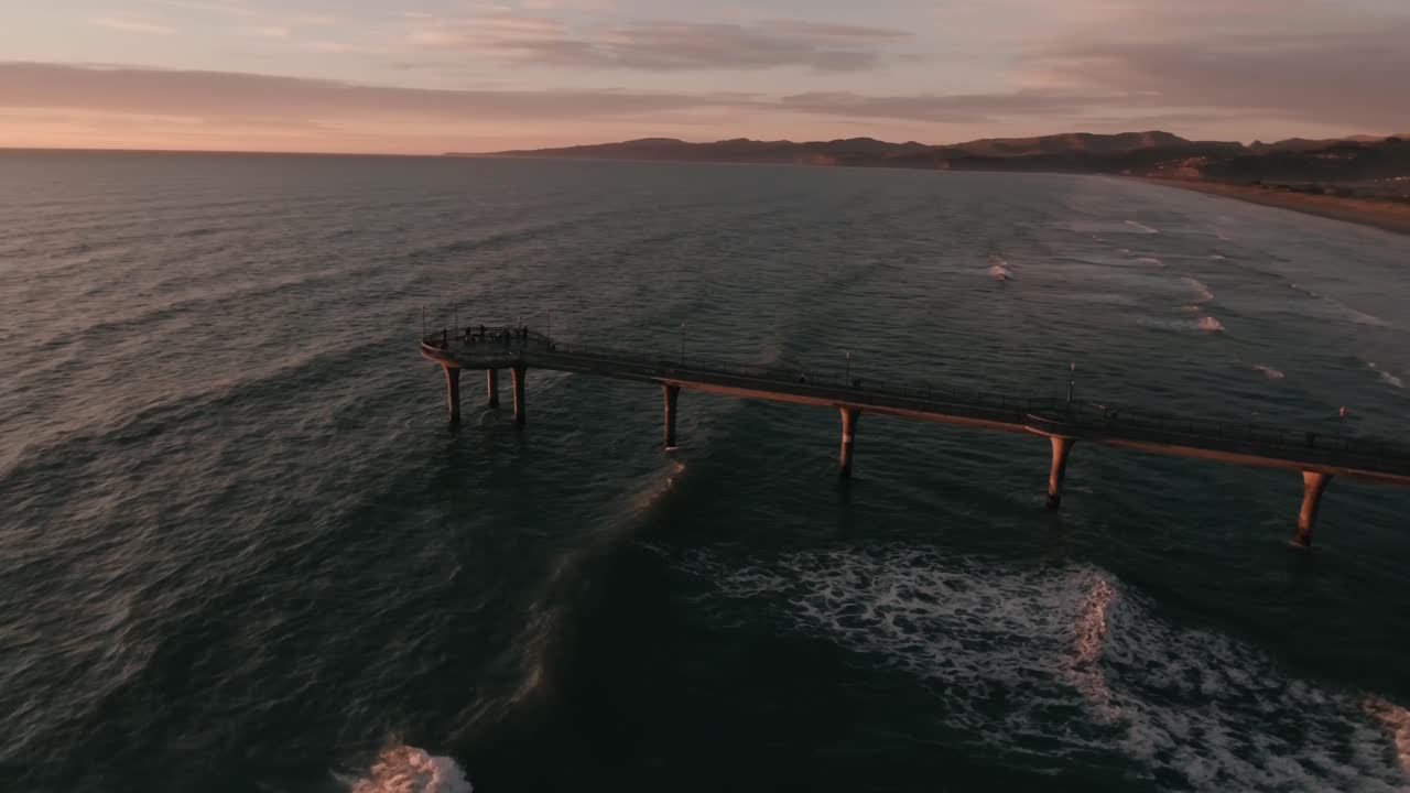 A revolving aerial view of the New Brighton Pier in Christchurch, New Zealand at sunrise.