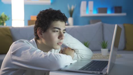 niño soñoliento y agotado mirando la computadora portátil. hora de dormir.