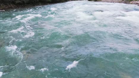 Aerial-view-of-a-powerful-river-flowing-through-a-forest-and-creating-white-water-rapids