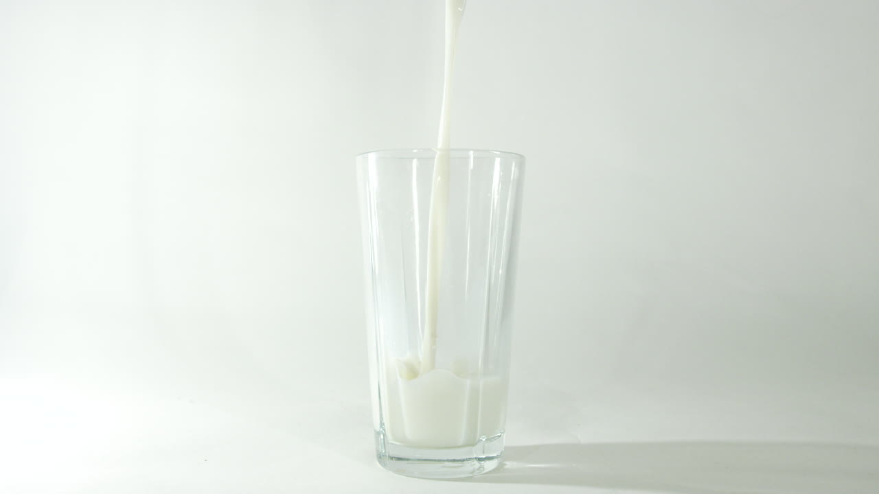 imágenes en cámara lenta de la leche que se vierte en un vaso con un fondo blanco limpio