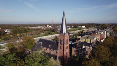 parish st. antonius of padua church in dutch town nijverdal seen from above on a sunny day with the tower rising above countryside landscape and train station tunnel in the background