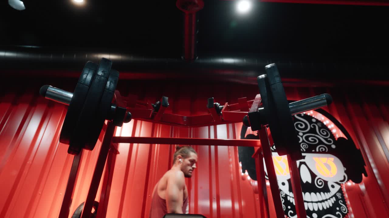 A man is preparing gym equipment by loading weight plates onto a machine bar. Concept of workout preparation, discipline, and fitness training