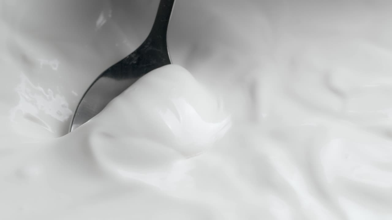 Optagelse af glidende baggrund med en ske i hvid creme.