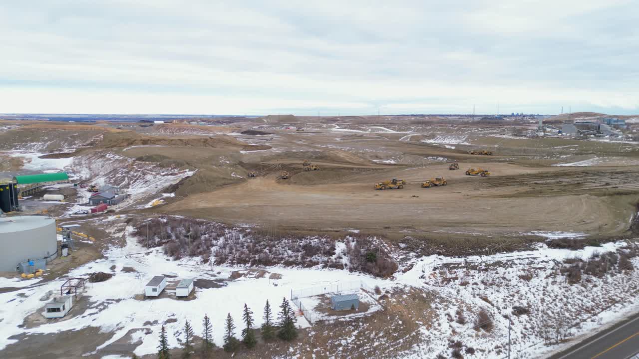 un sitio de construcción en calgary spyhill se ve desde el punto de vista de un dron aéreo donde los raspadores de tractores de ruedas trabajan para quitar la tierra