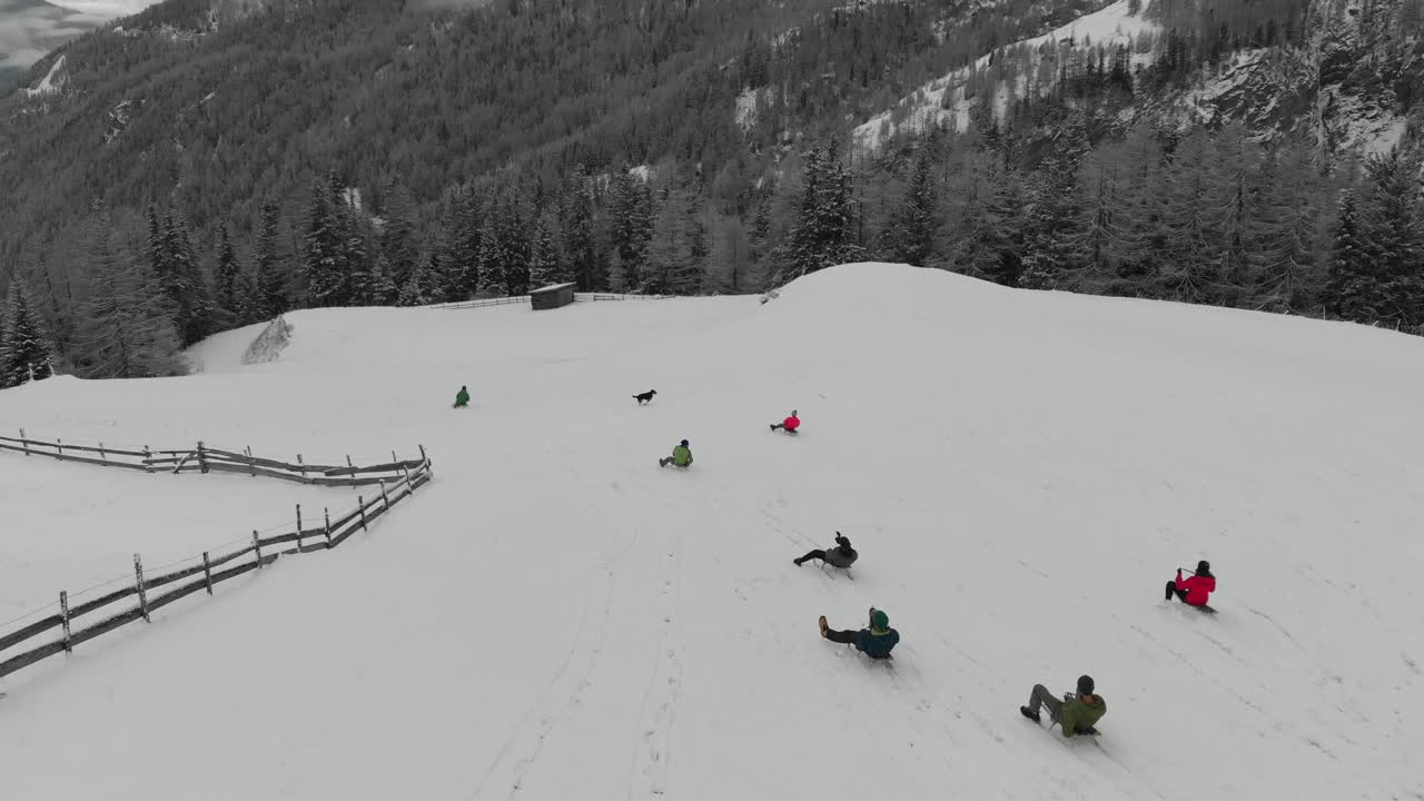 People sledding down a snowy hill in the mountains