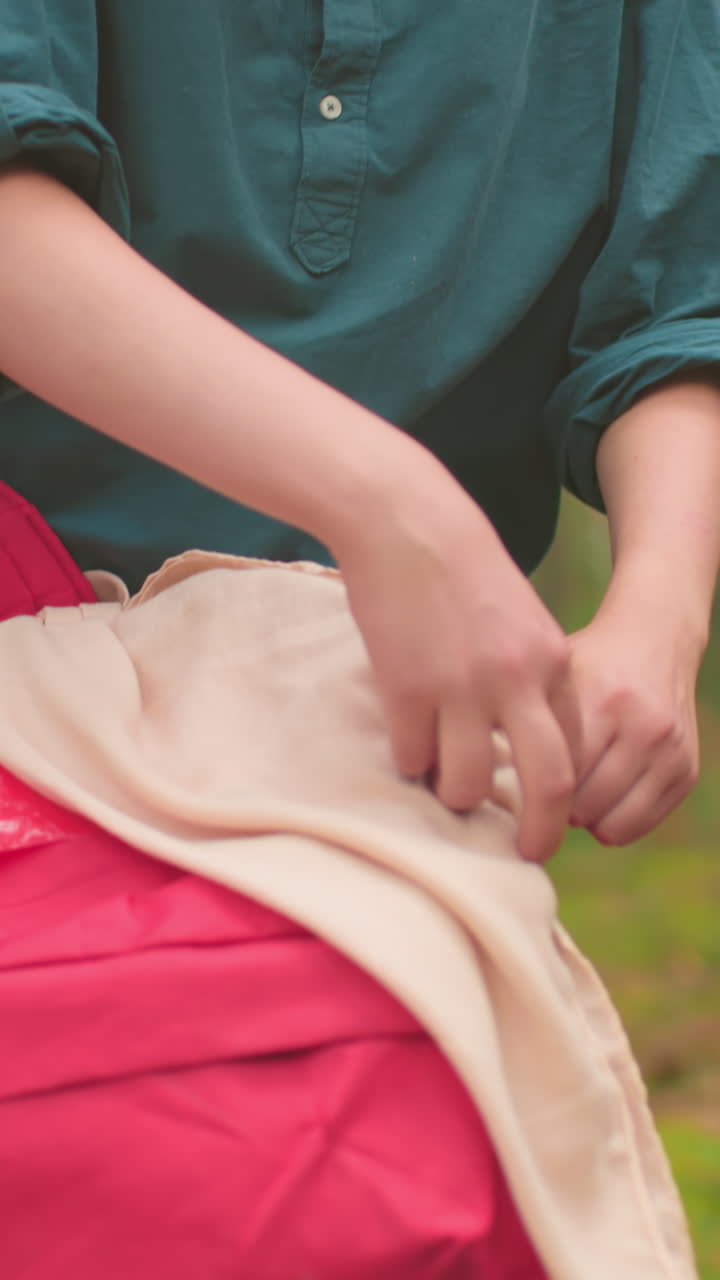 두 명의 젊은 산책객이 평온한 숲을 고, 배을 들고, 녹색 옷을 입은 여자가 빨간 가방을 열기 시작할 때 쓰러진 나무에 접근합니다.