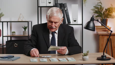 rich caucasian senior businessman counting money cash calculate earnings income profit at home