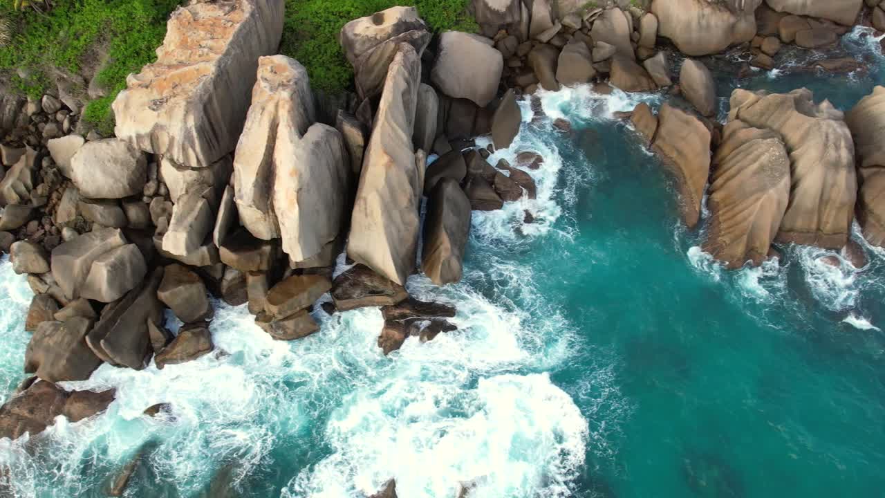 Ripresa aerea con drone della spiaggia di North East Point, enormi massi rocciosi con onde che si infrangono e acqua turchese, Mahe Seychelles 60 fps.