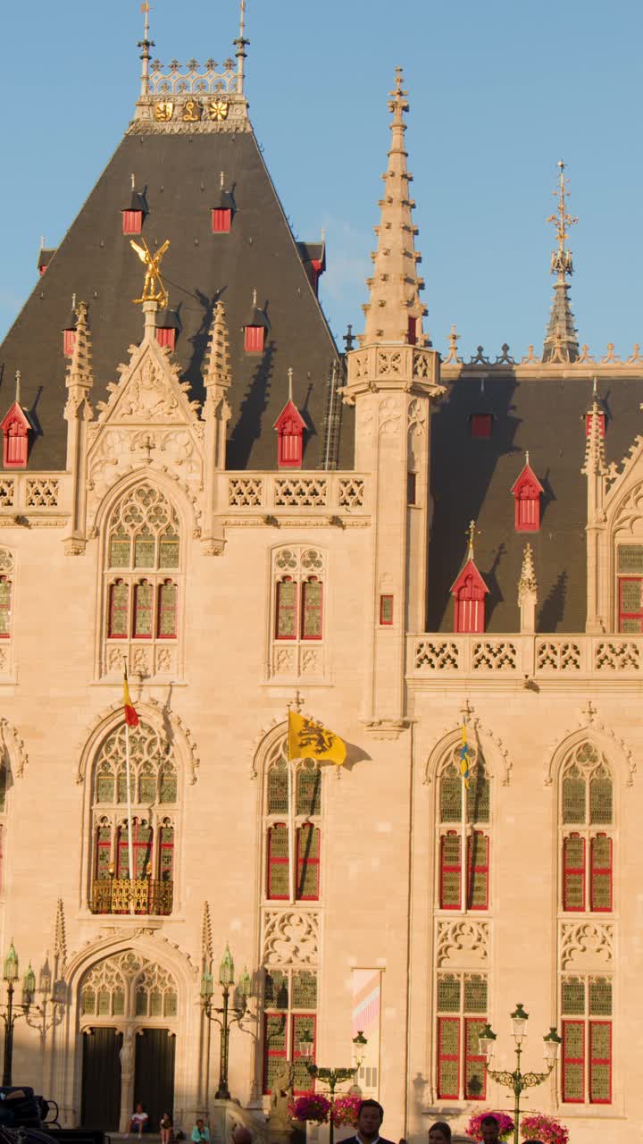 La telecamera si muove lentamente sull'ornata facciata gotica del municipio di Bruges durante la luce del tramonto.