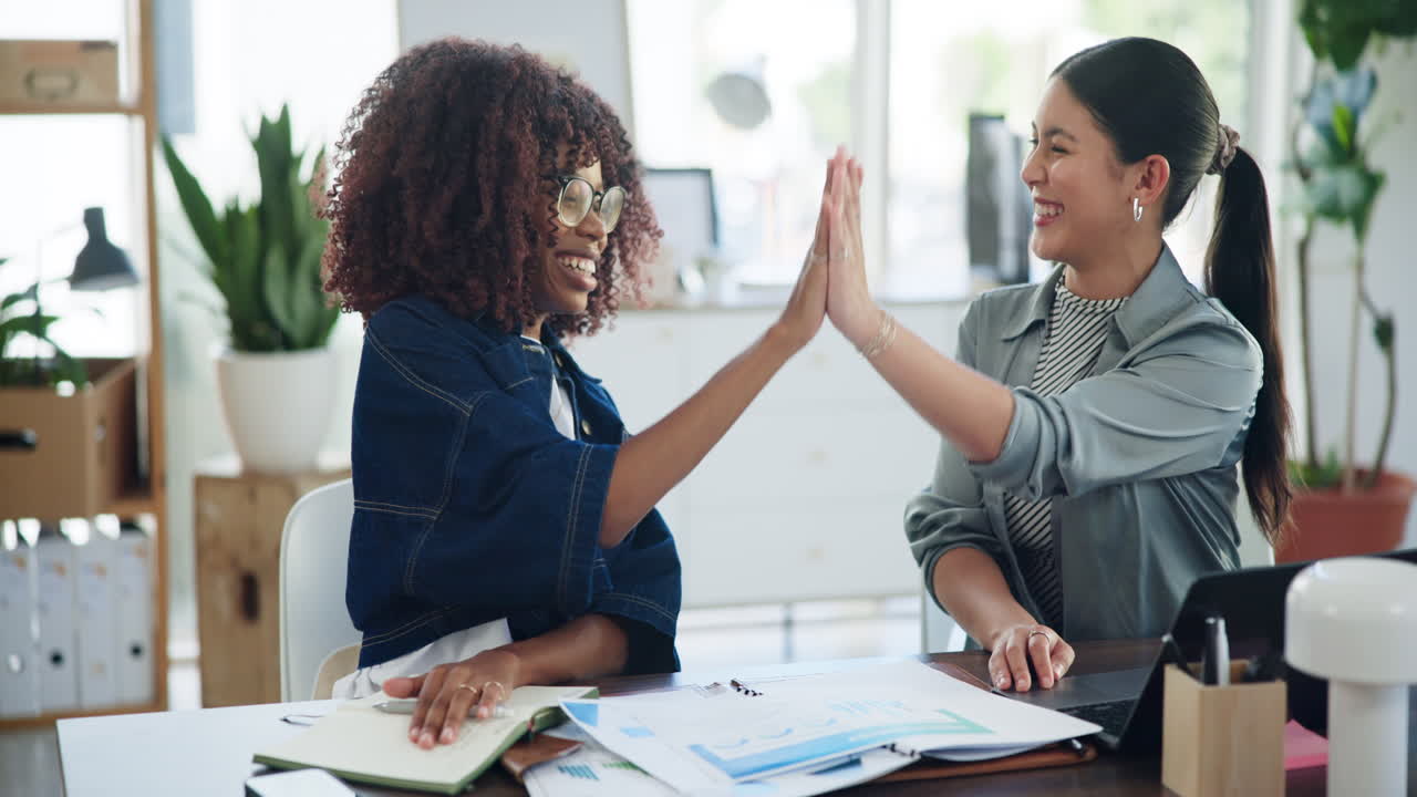 Two Happy Businesswomen High-Fiving and Collaborating in a Modern Office