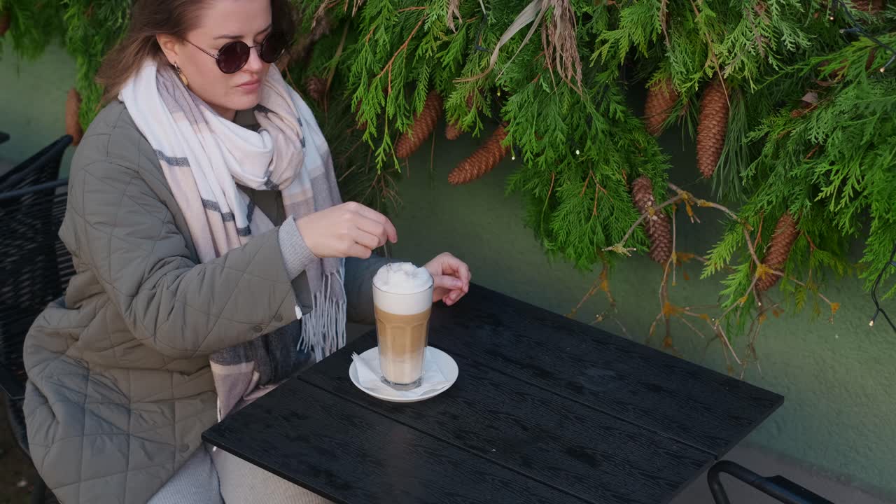 Woman enjoying a latte in a cozy outdoor cafe