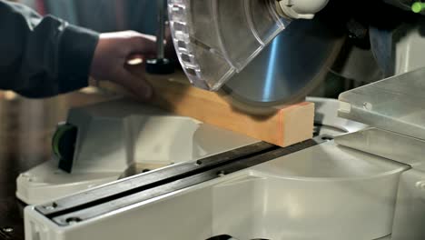 close-up of a man's hand working on a machine with a circular saw