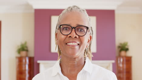 joyful senior woman with glasses smiling brightly at home, expressing happiness, copy space