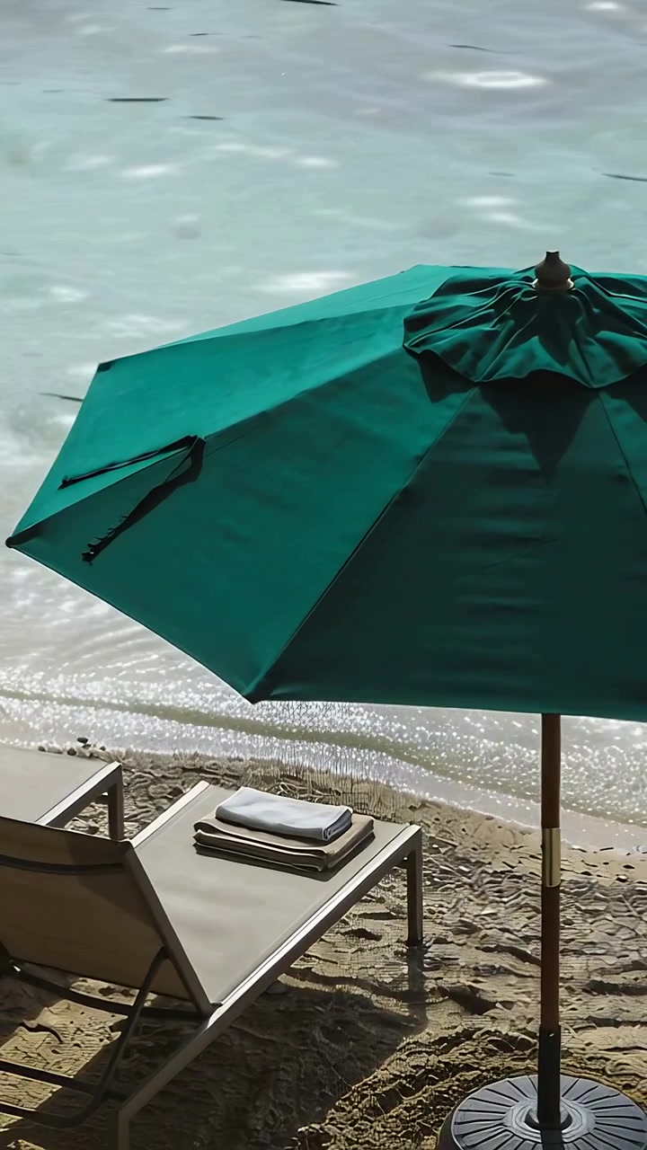 Video verticale: che rivela il palo verde di un ombrellone mentre la telecamera si sposta verso il basso sulla riva sabbiosa