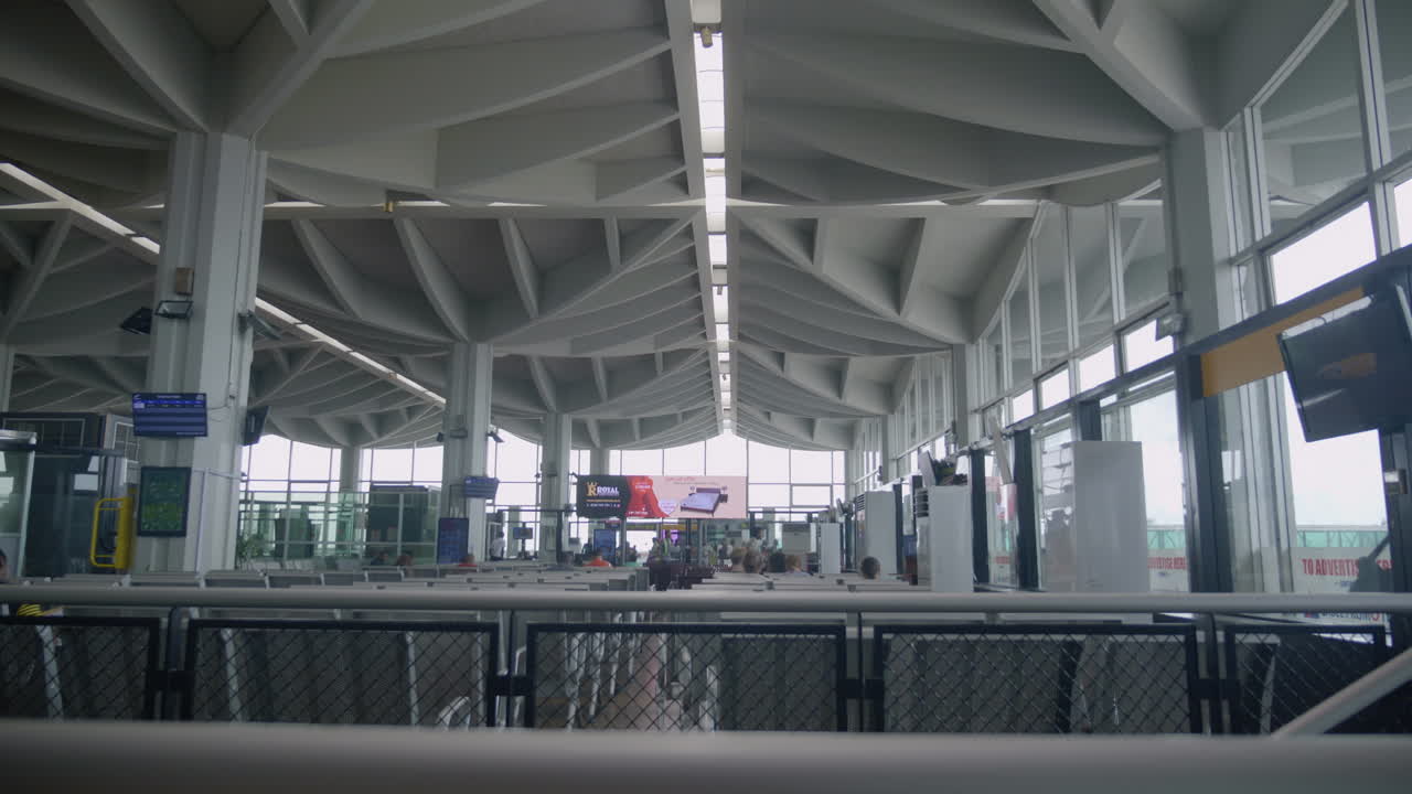 Interior view of a modern airport terminal building with unique ceiling architecture and people