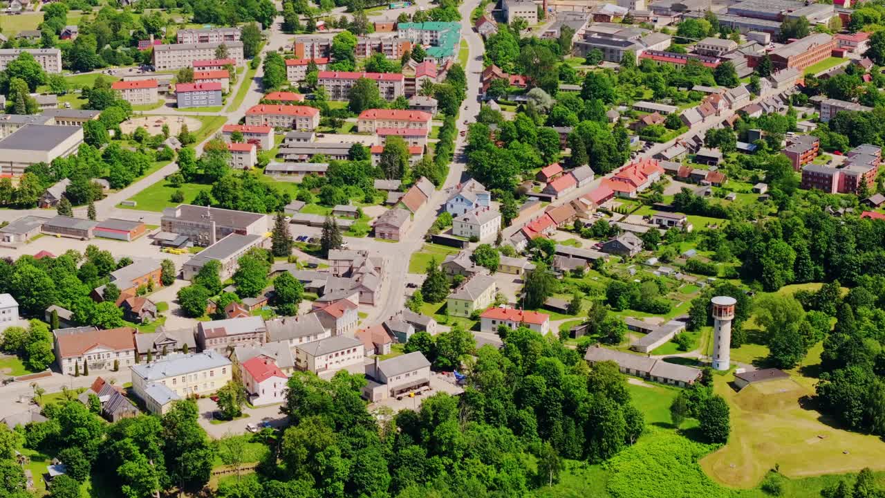 Drone turns over Aizpute town center revealing colorful rooftops, summer shot