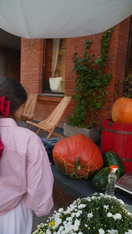 young woman with pink shirt and red scarf viewing pumpkins on a city street